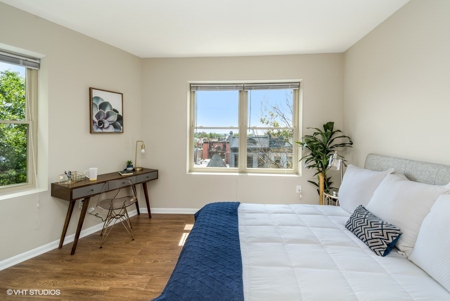 a bedroom with a large bed and two windows